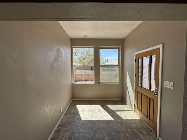 interior space with baseboards, a textured ceiling, and stone finish flooring