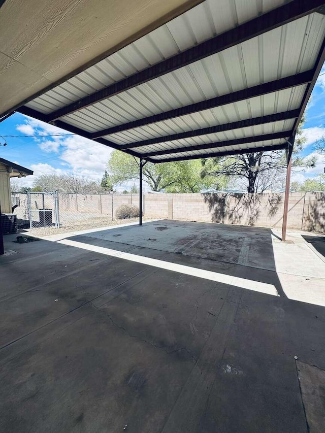 view of parking / parking lot with fence and a carport