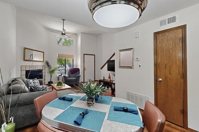 dining room with visible vents, a ceiling fan, wood finished floors, and a fireplace