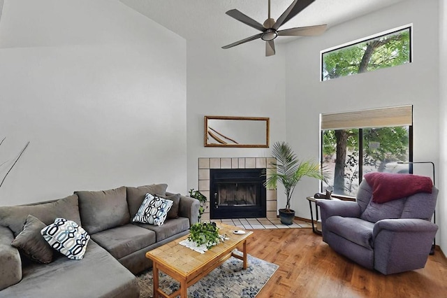 living area with ceiling fan, a wealth of natural light, wood finished floors, and high vaulted ceiling