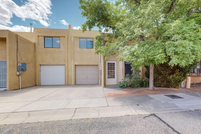 view of property with an attached garage, stucco siding, and concrete driveway