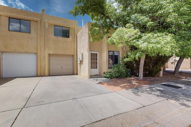 adobe home featuring a garage, driveway, and stucco siding