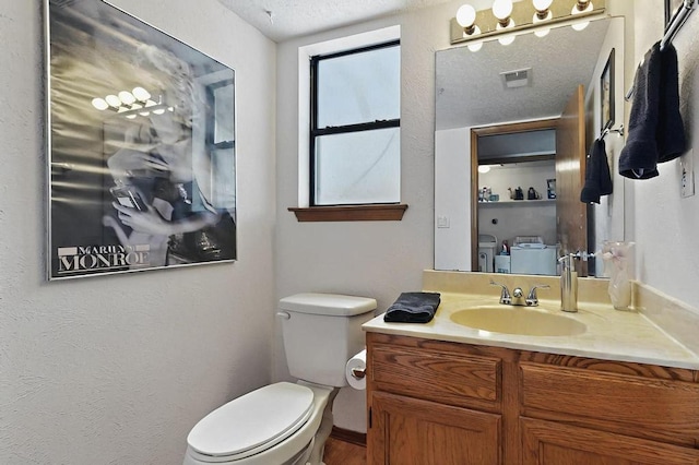 bathroom with toilet, a textured ceiling, visible vents, and vanity