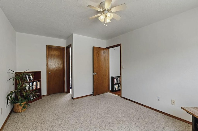 unfurnished bedroom featuring baseboards, a ceiling fan, a textured ceiling, and carpet floors