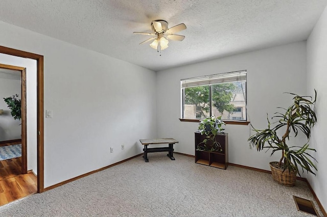 living area with visible vents, a ceiling fan, a textured ceiling, and carpet flooring