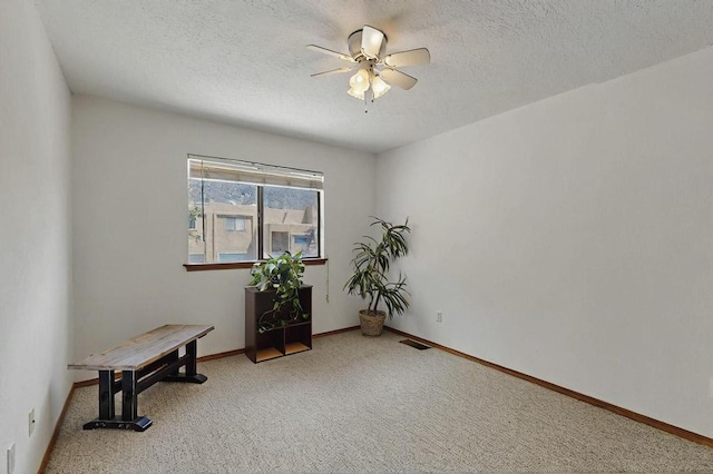 interior space featuring carpet floors, a textured ceiling, ceiling fan, and visible vents
