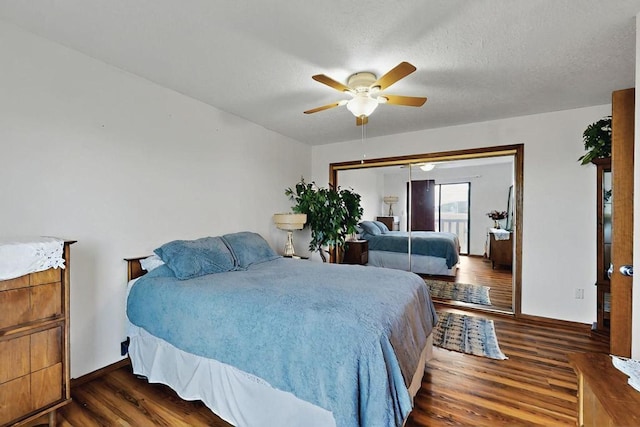 bedroom featuring baseboards, ceiling fan, dark wood-style floors, and a textured ceiling