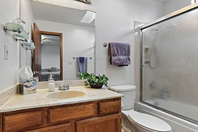 bathroom featuring toilet, bath / shower combo with glass door, and vanity