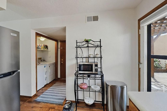 interior space with dark wood-style flooring, independent washer and dryer, visible vents, light countertops, and stainless steel appliances