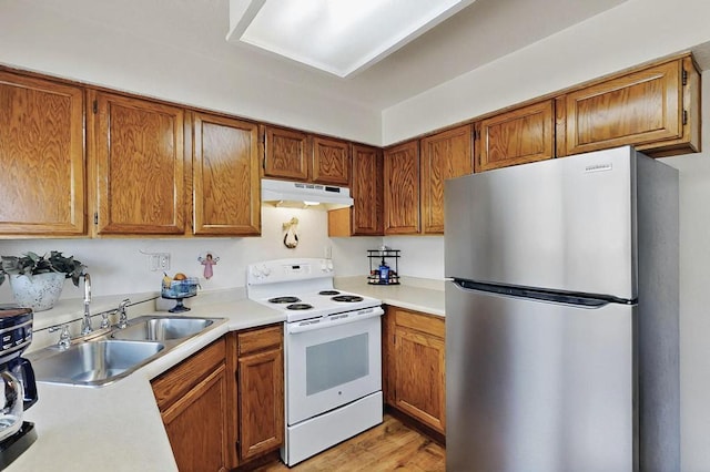 kitchen featuring freestanding refrigerator, white electric range, light countertops, under cabinet range hood, and a sink