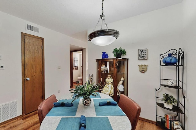 dining space with baseboards, light wood finished floors, and visible vents