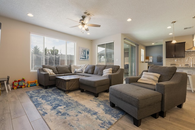 living room with visible vents, a ceiling fan, and light wood-type flooring