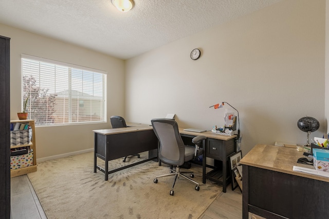 office space featuring light wood-type flooring, a textured ceiling, and baseboards