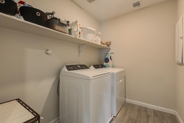 clothes washing area featuring independent washer and dryer, laundry area, light wood finished floors, baseboards, and visible vents
