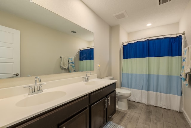 full bathroom featuring toilet, visible vents, a sink, and wood finished floors