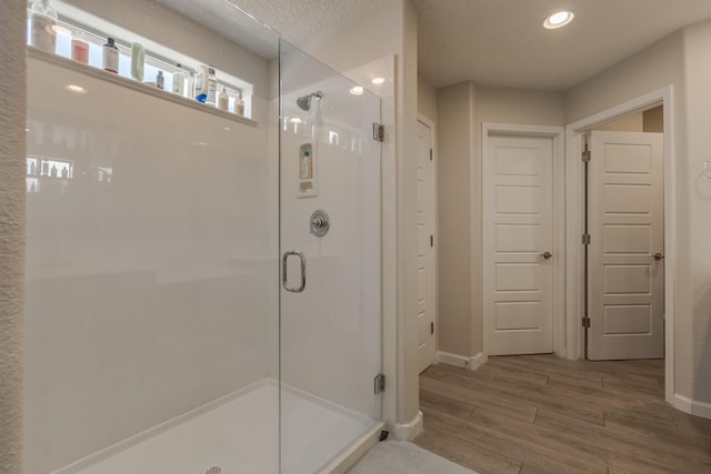 bathroom with baseboards, a stall shower, recessed lighting, and wood finished floors