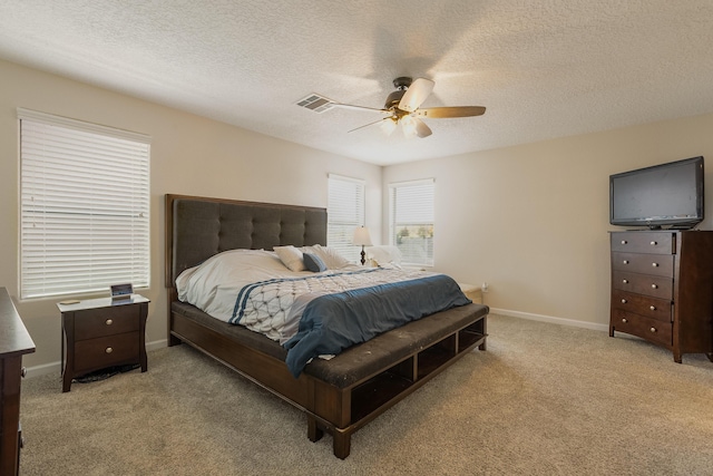 bedroom with ceiling fan, a textured ceiling, visible vents, carpet floors, and baseboards
