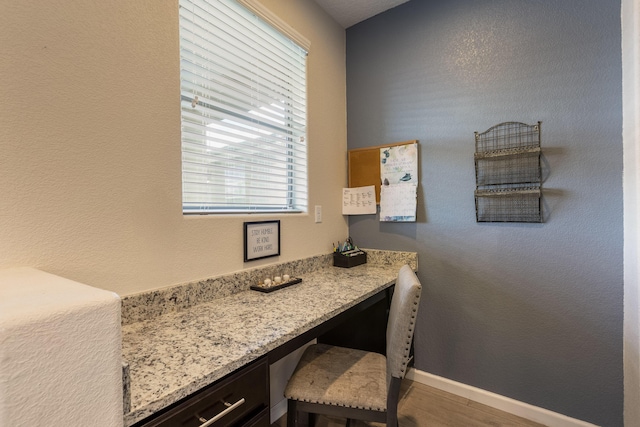 office featuring baseboards, built in desk, and wood finished floors