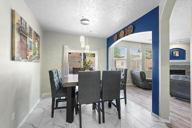 dining area featuring a textured ceiling, visible vents, baseboards, and marble finish floor