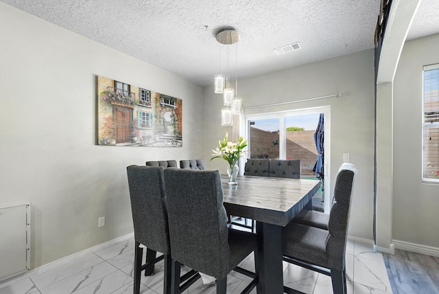 dining room featuring visible vents, an inviting chandelier, marble finish floor, baseboards, and a textured ceiling