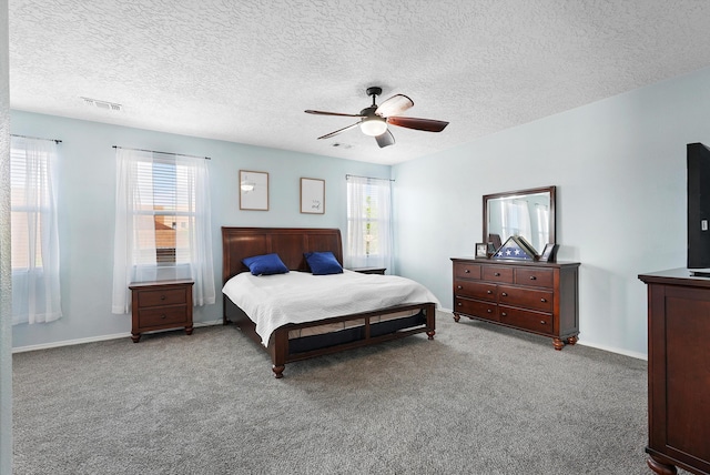 bedroom with ceiling fan, a textured ceiling, visible vents, baseboards, and carpet