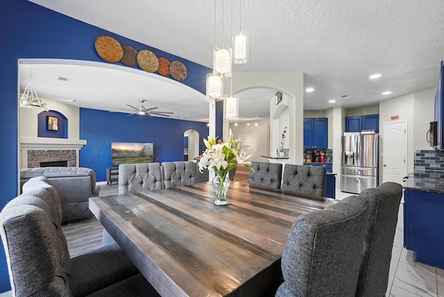 dining room with arched walkways, ceiling fan, and a textured ceiling
