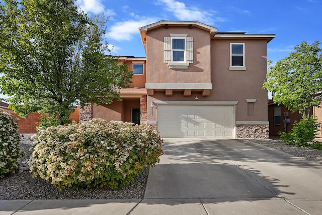 view of front of house featuring an attached garage, stucco siding, driveway, and stone siding