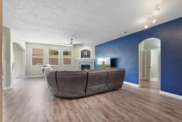living area with a ceiling fan, visible vents, wood finished floors, and a fireplace