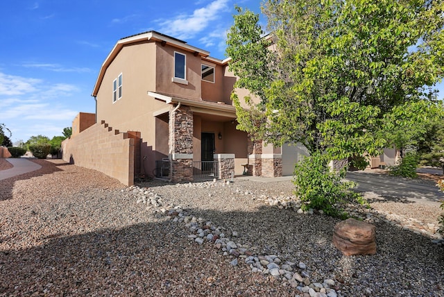view of front of property with fence, stone siding, and stucco siding
