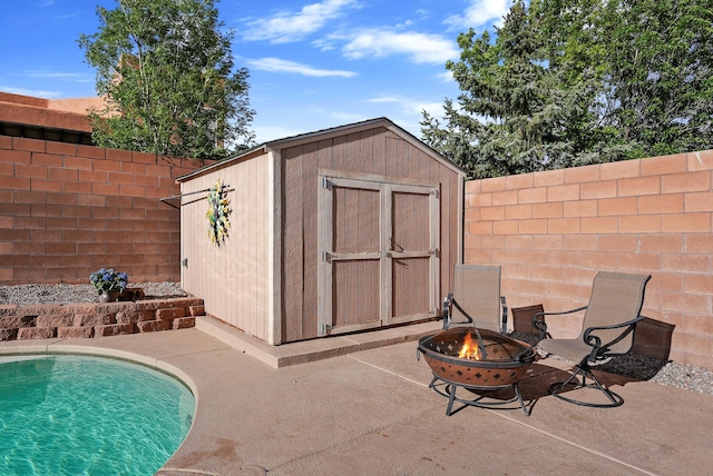 view of shed featuring a fenced backyard and an outdoor fire pit