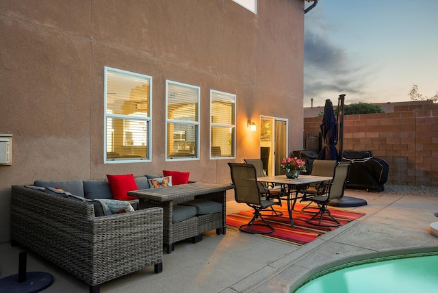 back of house at dusk featuring a patio area, fence, an outdoor hangout area, outdoor dining space, and stucco siding