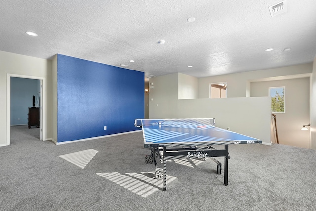 recreation room featuring carpet floors, a textured ceiling, and visible vents