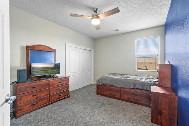 bedroom featuring ceiling fan, a textured ceiling, visible vents, a closet, and carpet flooring