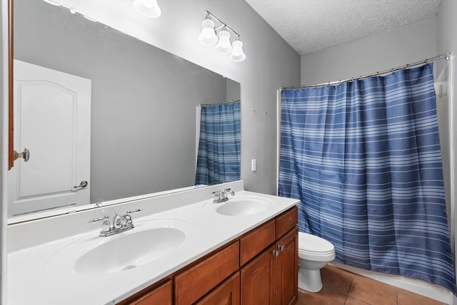 bathroom featuring double vanity, a sink, a textured ceiling, and toilet