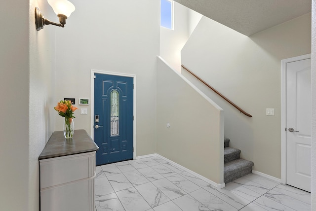 foyer featuring baseboards, a high ceiling, stairs, and marble finish floor