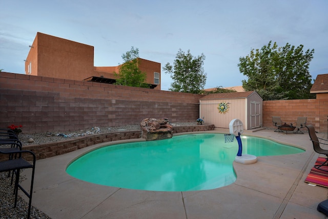 view of swimming pool with a storage shed, a patio, an outbuilding, and a fenced backyard