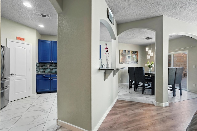 interior space featuring arched walkways, a textured ceiling, visible vents, and baseboards