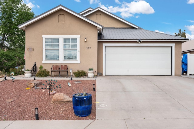 single story home with driveway, stucco siding, a garage, and metal roof