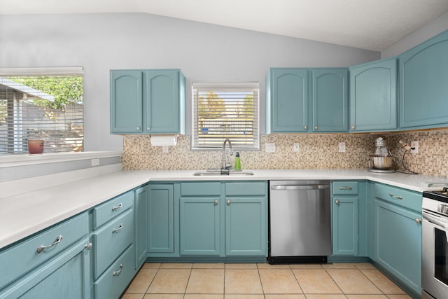 kitchen with vaulted ceiling, a sink, light tile patterned floors, and appliances with stainless steel finishes