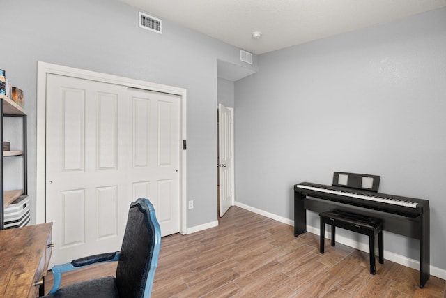 office area with baseboards, light wood-type flooring, and visible vents