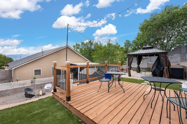 wooden terrace featuring a gazebo and a fire pit