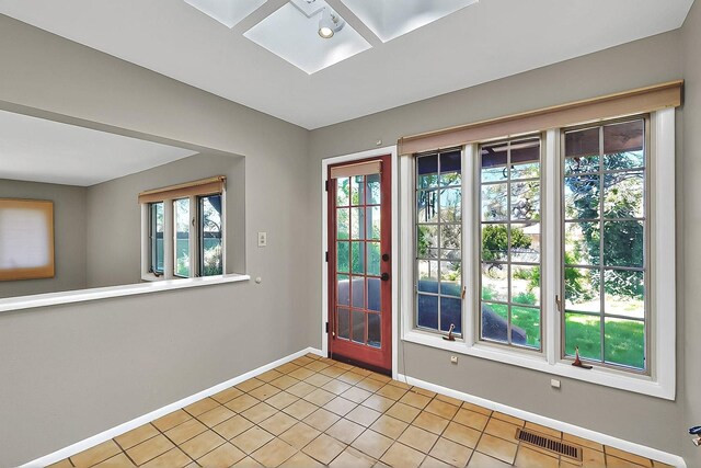 entryway with baseboards, light tile patterned floors, visible vents, and a skylight