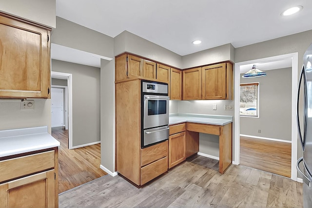 kitchen featuring stainless steel appliances, baseboards, a warming drawer, and light wood-type flooring