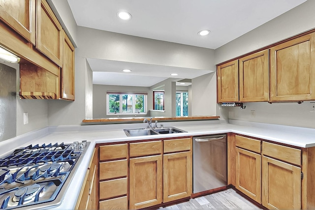 kitchen featuring recessed lighting, light countertops, brown cabinets, a sink, and appliances with stainless steel finishes