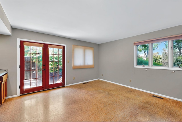 unfurnished room featuring baseboards, french doors, and a wealth of natural light