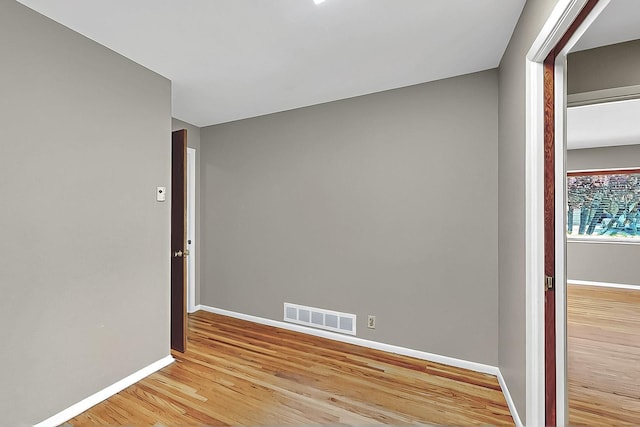 empty room featuring baseboards, light wood-style flooring, and visible vents