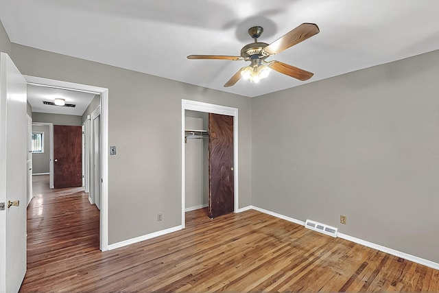 unfurnished bedroom with ceiling fan, baseboards, wood finished floors, visible vents, and a closet