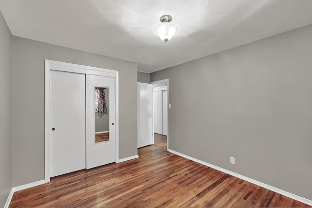 unfurnished bedroom with baseboards, a closet, and wood finished floors