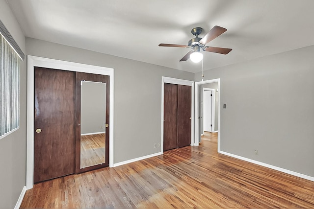 unfurnished bedroom with a ceiling fan, baseboards, multiple closets, and light wood finished floors