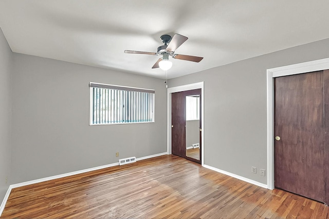 unfurnished bedroom with baseboards, wood finished floors, and visible vents